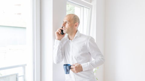 businessman talking smartphone looking through office window